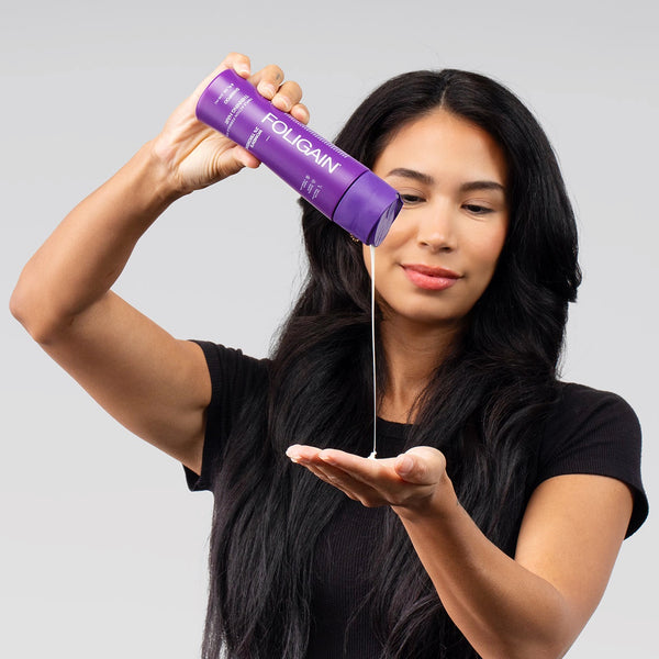 Woman holding a purple Foligain product against a gray background